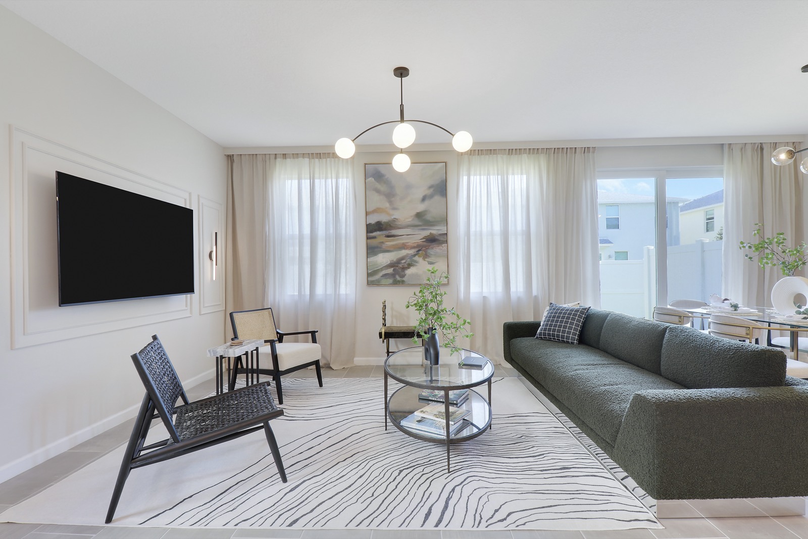 Living room at 261 Osprey Preserve with a green sofa, a black sling chair and a chandelier of white globes