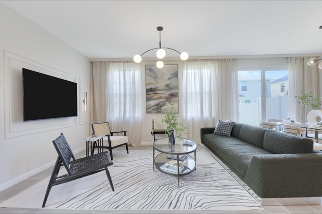 Living room with a green sofa, a black sling chair and a chandelier of white globes, the TV wall at the left