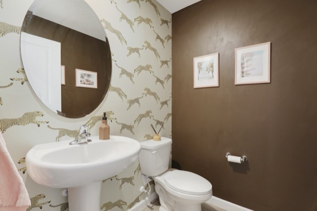 Powder room with cheetah wallpaper, a round mirror, a pedestal sink and a chocolate-brown accent wall