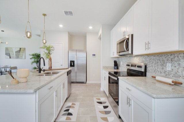 Kitchen run with the range and round mosaic backsplash at the right and the island at the left