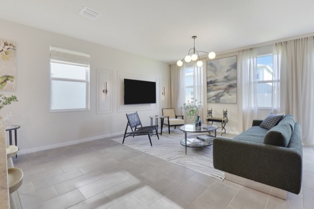Wide view of the living room from the kitchen side, the sofa at the right and the TV wall at the far end
