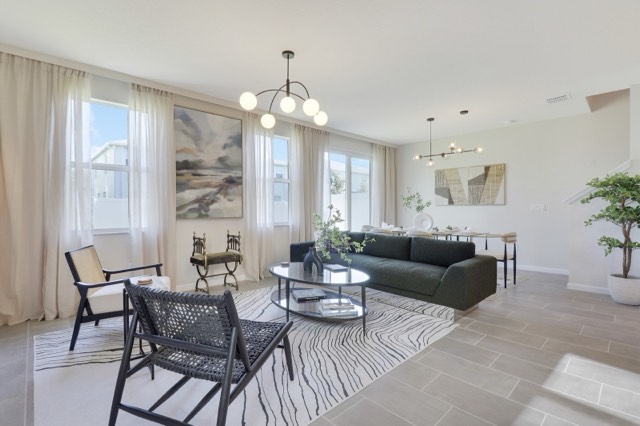 Living room from the window corner, cream drapes at the left and the dining area behind the sofa