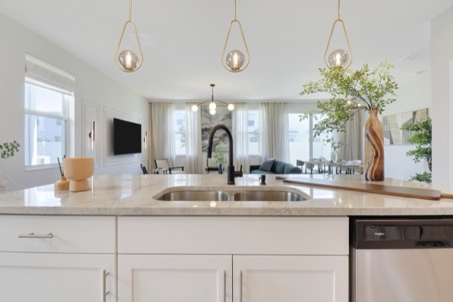 Kitchen island with a black faucet and sink, looking past it into the living room