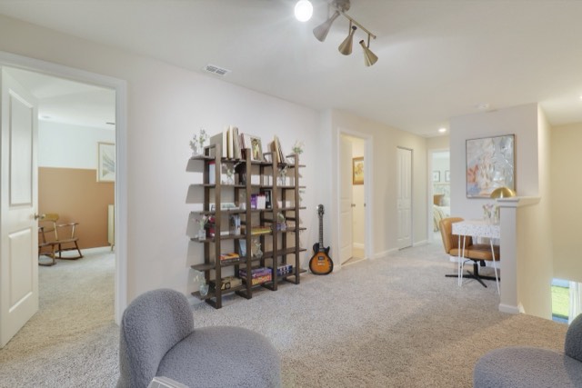 Upstairs loft with a tall bookshelf, a guitar and two gray swivel chairs, a bedroom door at the left