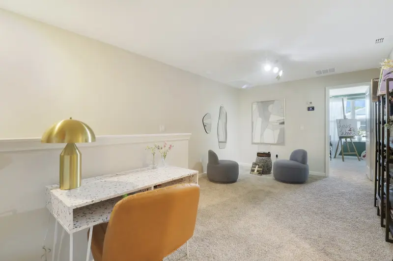 Loft desk nook at 261 Osprey Preserve with a white desk, a brass lamp and a tan chair