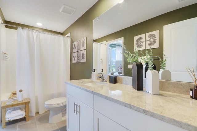 Bathroom with olive walls, a tub with a white shower curtain and a white shaker vanity