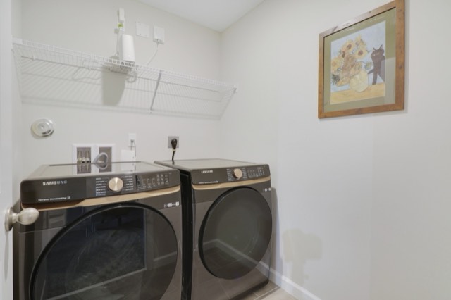 Laundry room with a front-load washer and dryer under a wire shelf, a framed print above