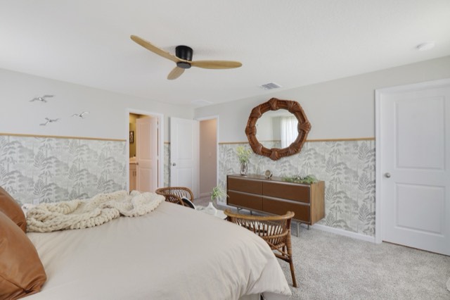 Primary bedroom with a wood dresser under a round rattan mirror and a white panel door