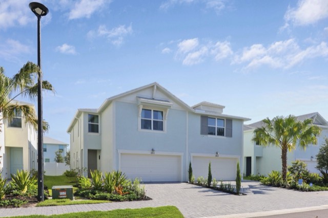 Blue-gray two-story townhomes and their garages seen at an angle from the street