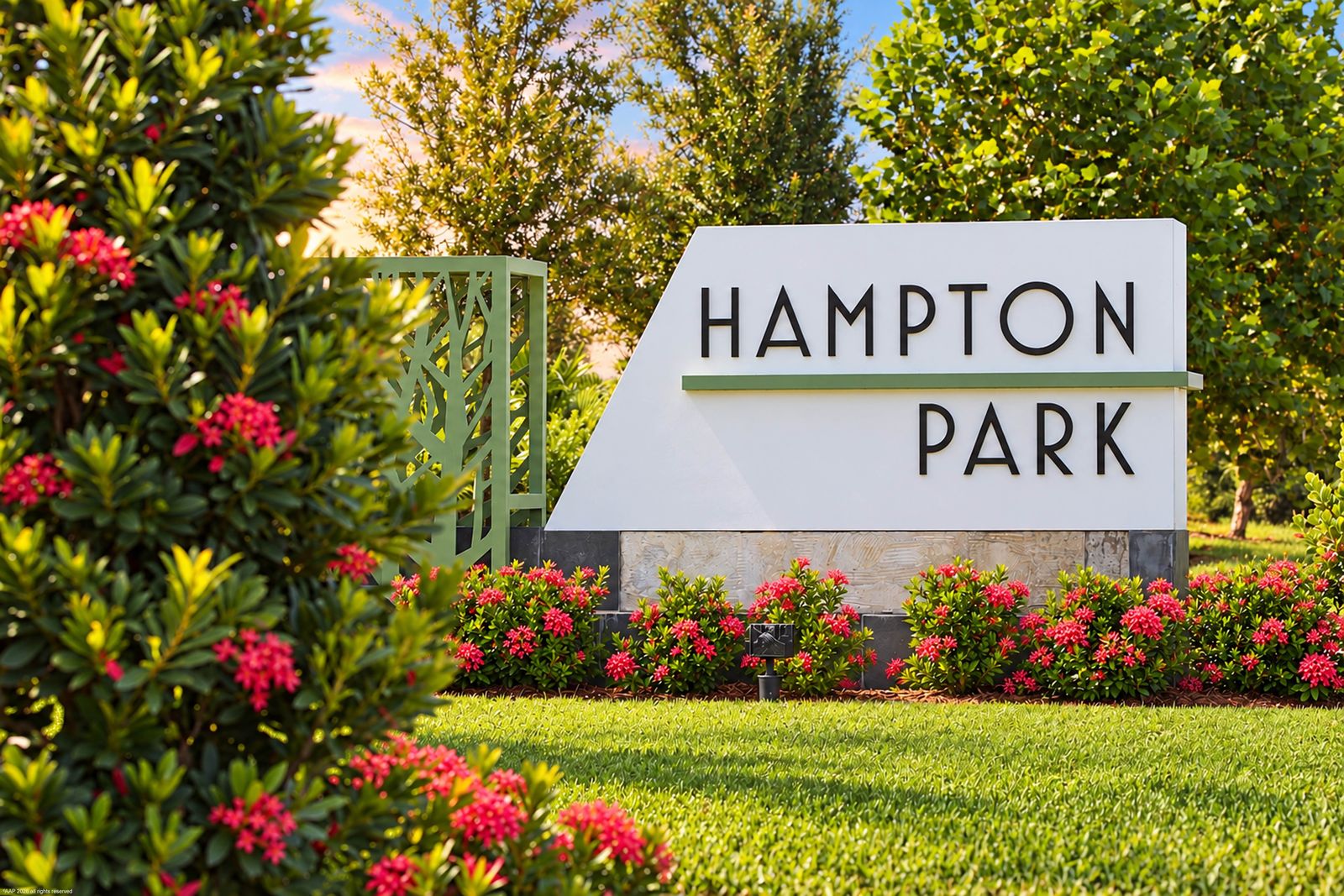 Hampton Park monument sign framed by flowering shrubs
